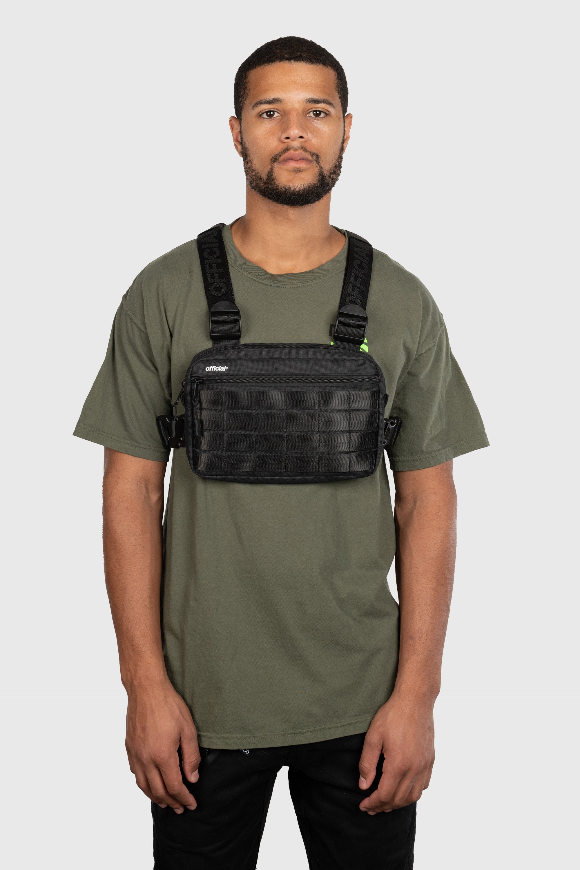Compact Essential Chest Bag in black front view on person. Four rows of molle straps and small OFFICIAL® logo white top left corner.